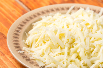 Chopped cheese on the plate above wooden board