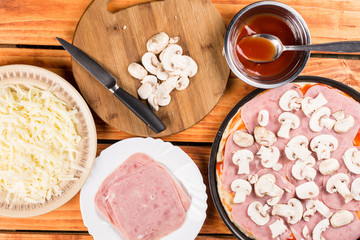 Flat lay above table with pizza ingredients, mushrooms ham ketchup