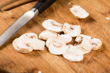 Sliced raw fresh mushrooms on the wooden board with knife