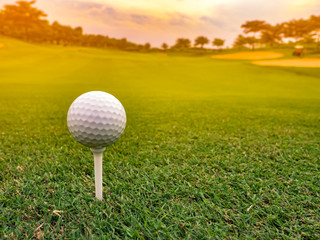 Close up of professional golf ball on a tee, ready for tee off shot, sunrise background