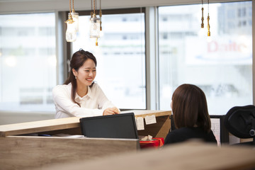 A young lady is talking to a receptionist