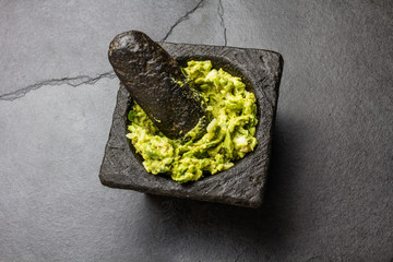 Traditional latin american mexican sauce guacamole in stone mortar, slate gray background