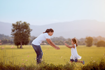 Naklejka na ściany i meble Cute asian child girl running to her mother to give a hug in the field in vintage color tone