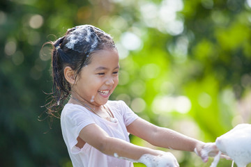 Happy asian child girl having fun to bath and play with foam in outside