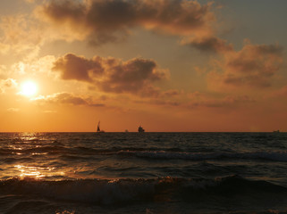 Dramatic sunset with clouds over mediterranean sea, yacht and ship on horizon, Ashdod, Israel.