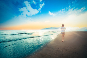 Obraz premium Beautiful young girl running and playing side sea on sand.