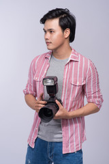 Fototapeta premium Young asian photographer holding digital camera, while working in studio