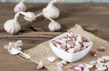 a garlic in bowl on old wooden table with big  garlic background