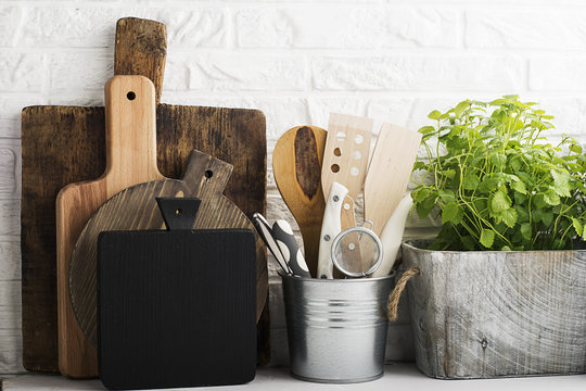 Kitchen still life on a white brick wall background: various cutting boards, tools, greens for cooking, fresh vegetables. Selective focus.