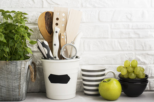 Kitchen still life on a white brick wall background: various cutting boards, tools, greens for cooking, fresh vegetables. Selective focus.