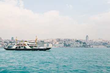 The ship sails along the blue water of the Bosphorus against the backdrop of a beautiful view of the European part of Istanbul. Scenic panoramic view. Travel, rest, vacation.
