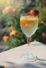A glass of white sangria with citrus and strawberry