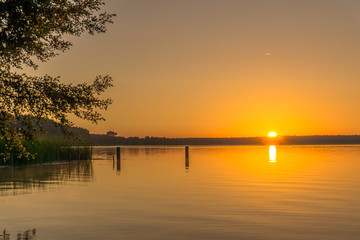 Naklejka na ściany i meble Sunrise over a small lake with trees