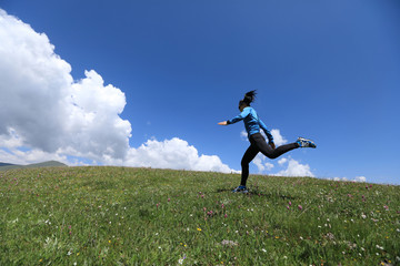 young fitness woman runner running jumping on grassland
