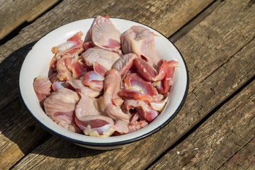 Raw chicken gizzards in metal enamelled bowl on rustic wooden table
