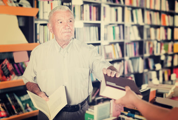 Senior male is purchasing new book in bookstore