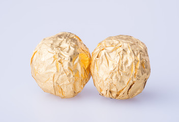 Chocolate ball in a gold foil paper on a background.