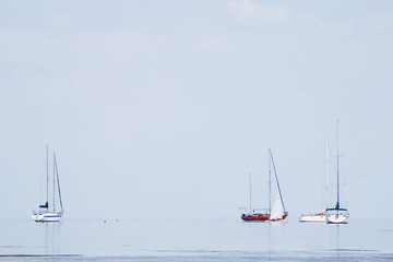 Sailing yacht in the blue sea with sails down, summer landscape