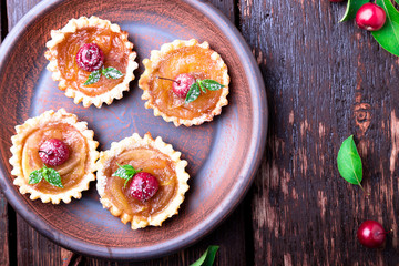 Apple caramel little tarts on brown rustic background. French tatin with paradise apple. Top view.