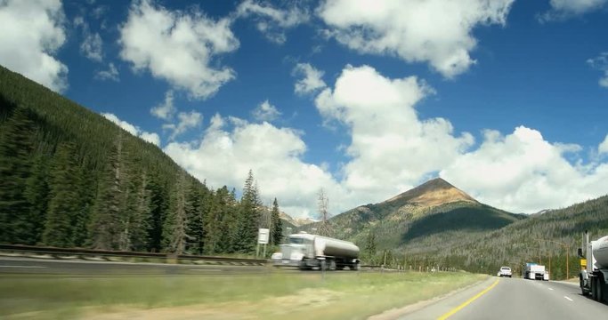 POV moving driving down rocky mountain highway clouds blue sky spring summer day I-70 Rocky mountains Colorado 4K