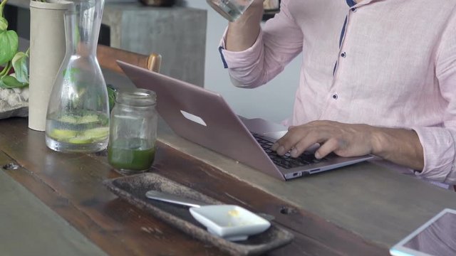 Man using laptop and drinking beverage sitting at home
