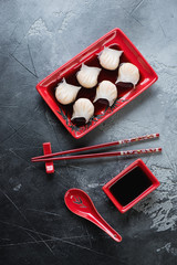 Top view of steamed prawn hargows in soy sauce, vertical shot on a grey stone surface