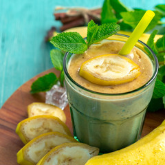 Banana smoothie and fresh banana on wooden background.