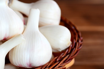 Raw garlic in a basket on a brown wooden background. Harvesting garlic bulbs concept. Fresh garlic background. Closeup