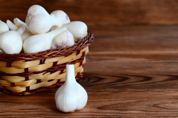 Raw garlic bulbs in a basket on a wooden background with empty place for text. Harvesting garlic concept. Young garlic background