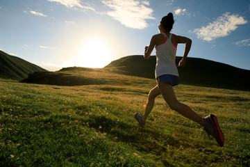 young fitness woman runner running on sunset grassland trail © lzf