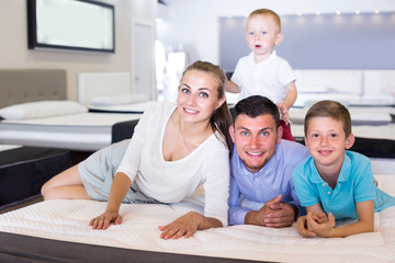 Man with female and children are testing quality of mattress