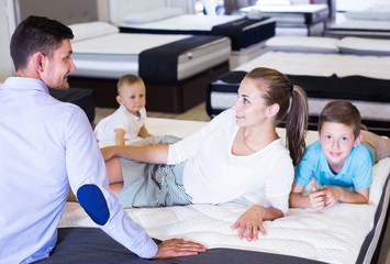 Smiling parents with two sons testing mattress in store