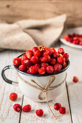 wild strawberry in a white Cup on wooden background