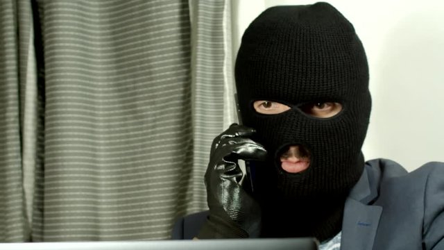 A Criminal With A Mask Using A Computer.