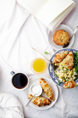 Breakfast in bed. Scrambled eggs with cheese croissants, raspberry muffin and black coffee. Morning treat concept. Vertical composition with copy space.
