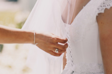 Woman fixes dress on bride's back