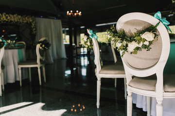 Garlands of white roses decorate grey chairs in the restaurant