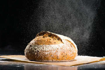 traditional round artisan rye bread loaf with walnut and seeds was sprinkled flour on wooden...