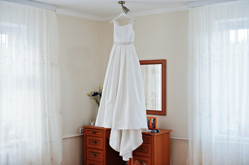 Fototapeta na wymiar Wedding dress hanging on the rack in the room.