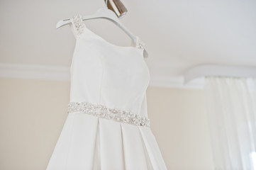 Wedding dress hanging on the rack in the room.