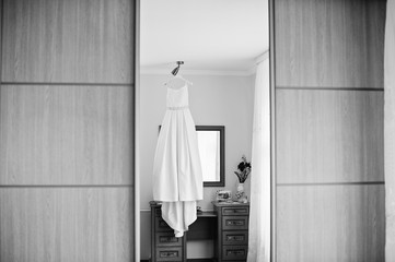 Fototapeta na wymiar Wedding dress hanging on the rack in the room. Black and white photo.