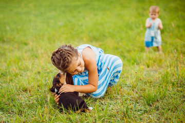 Girl hugs little puppy sitting on the field