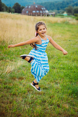 Little girl jumps on green field