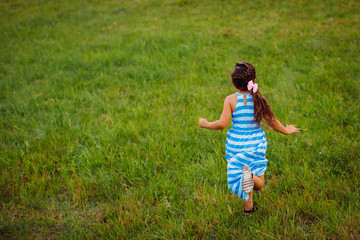 Fototapeta premium Little girl runs on green field