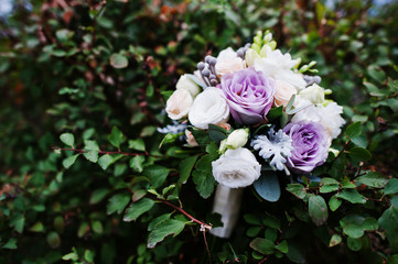 Close-up photo of a fantastic wedding bouquet laying on the bushes.