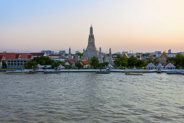 Fototapeta premium Wonderful ancient Pagoda of Wat Arun one of the most beautiful archaeological site view from Chao Phraya River side in twilight time from Bangkok, Thailand. (With warm sunlight effect) 