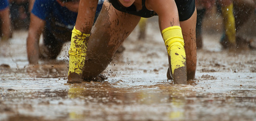 Mud race runners.Crawling,passing under a barbed wire obstacles during extreme obstacle race