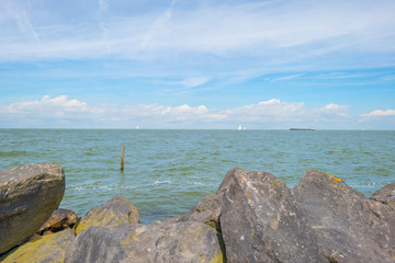 Coastline of a basalt stone dike along a lake in summer