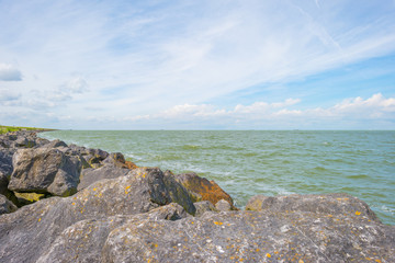 Coastline of a basalt stone dike along a lake in summer