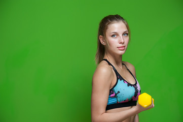 Young blonde woman standing with dumbbell